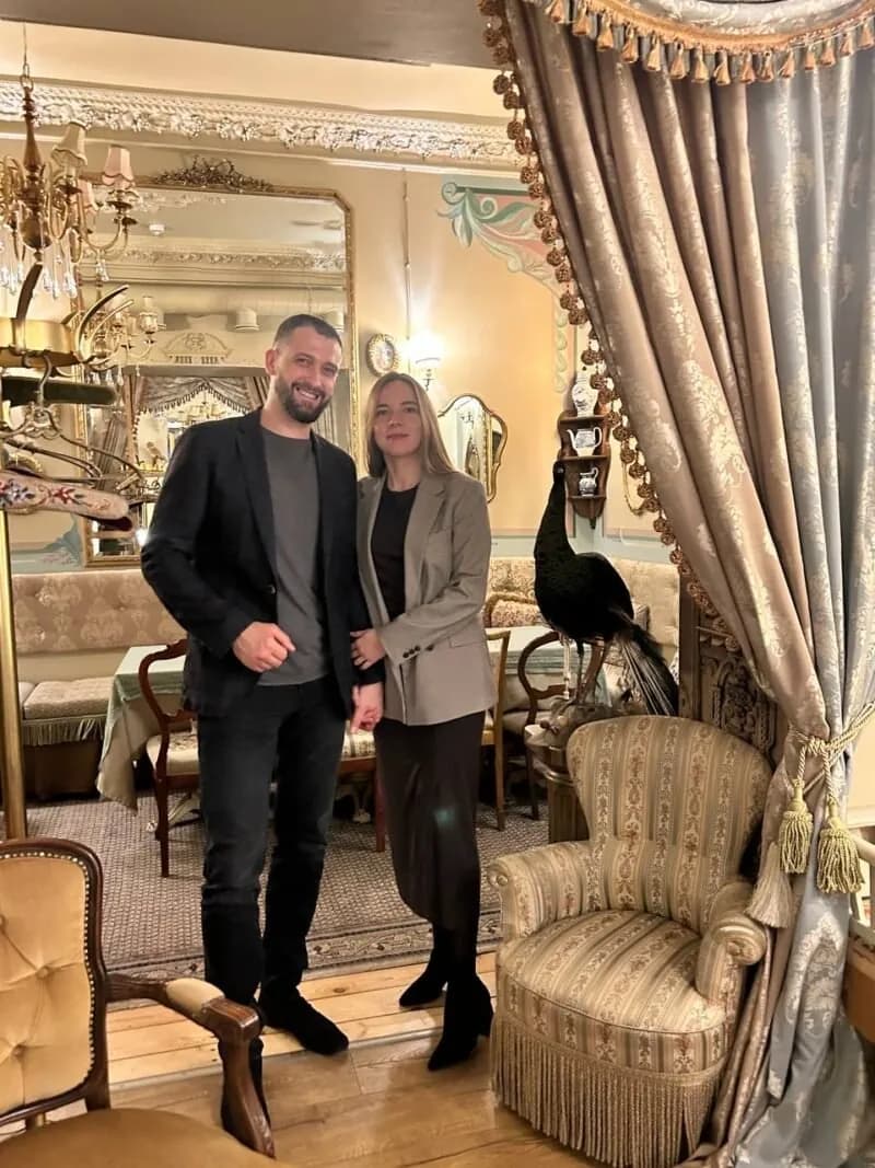 Therapy by Titov terapeiti Aleksejs Titovs and Darja Titova stāv kopā mājīgā, vēsturiskā istabā Rīgā.